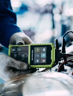 Technician testing a car battery with a digital battery tester